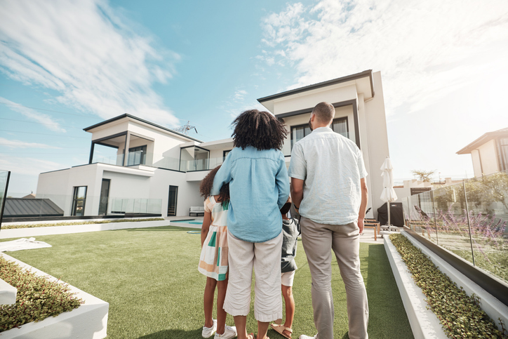 A family stands in front of a modern home, looking at their future house made possible with VP Capital Lending.