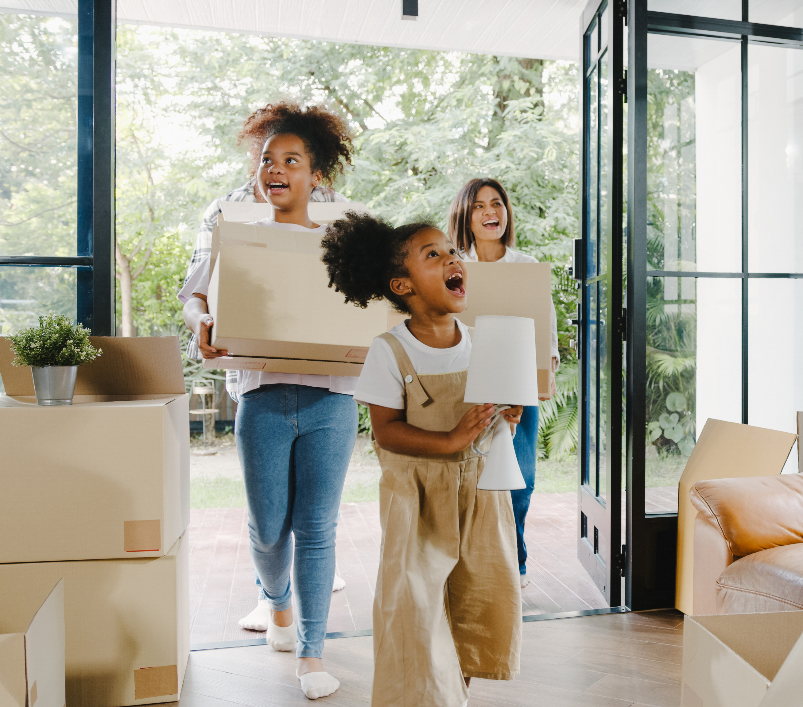 Excited family carrying moving boxes into their new home, symbolizing a successful home purchase with a 30-year fixed mortgage.