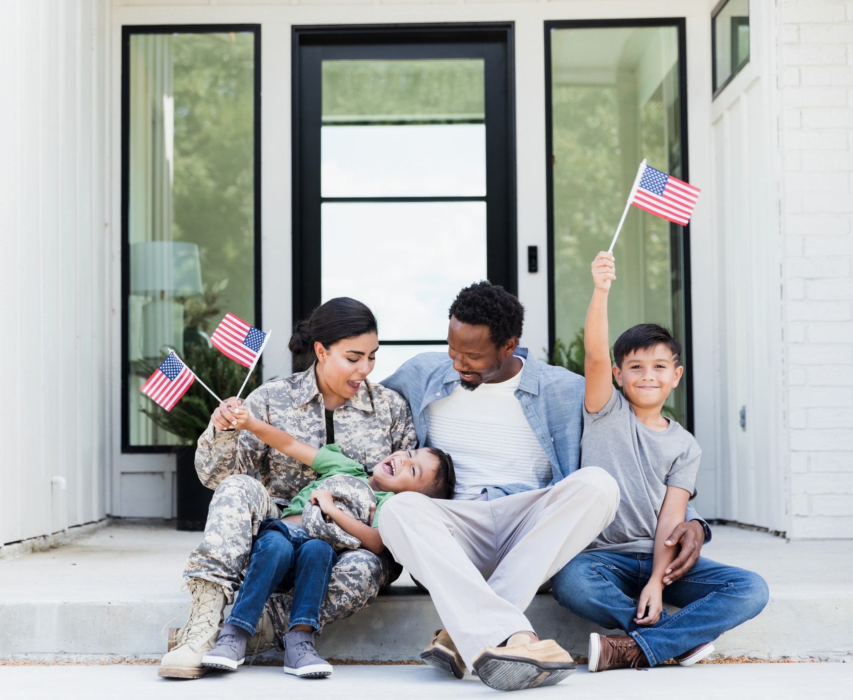 A military family sitting on their new home's porch, celebrating homeownership with VA loan benefits.