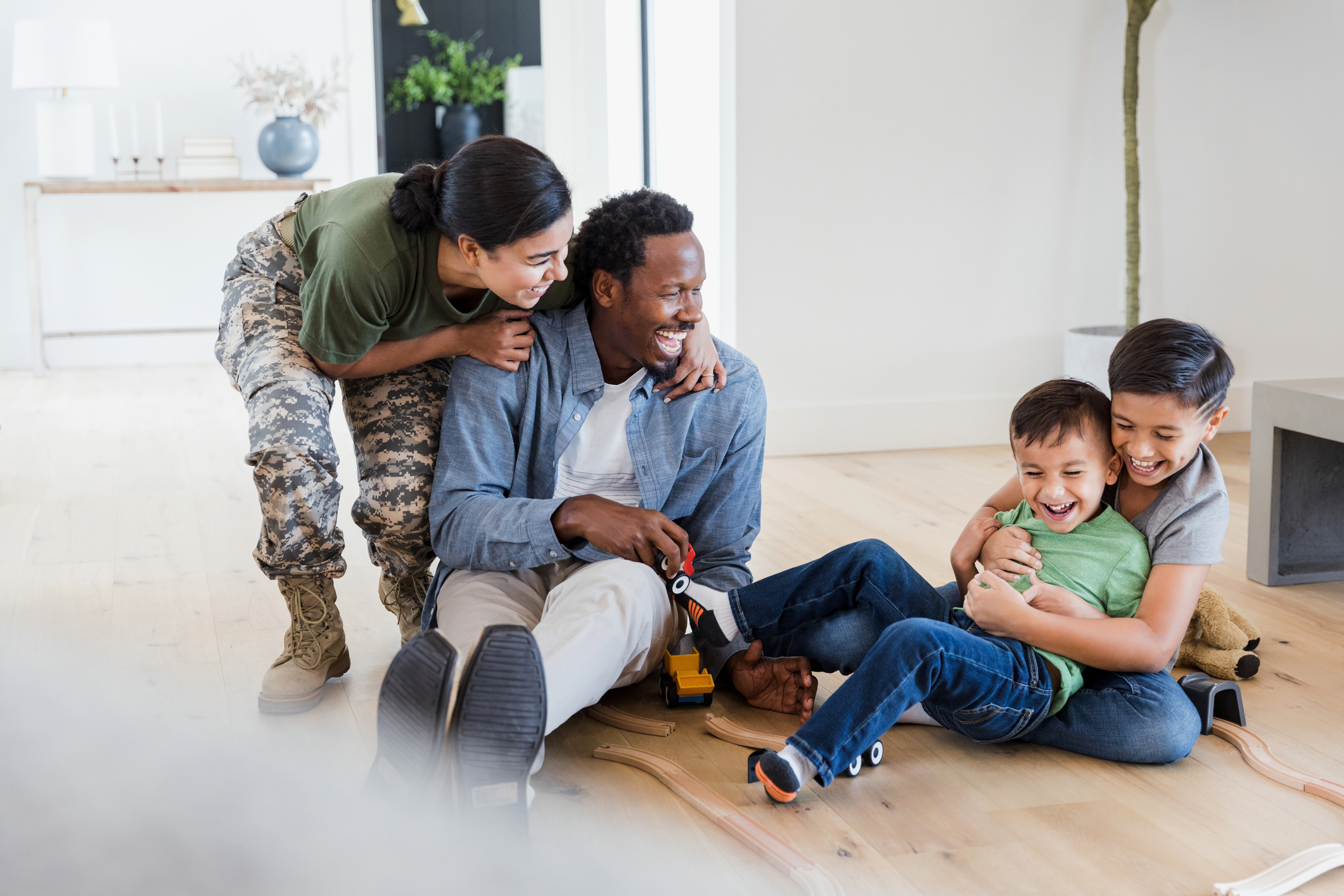 A smiling military family playing together at home, representing the financial security and affordability of VA home loans.