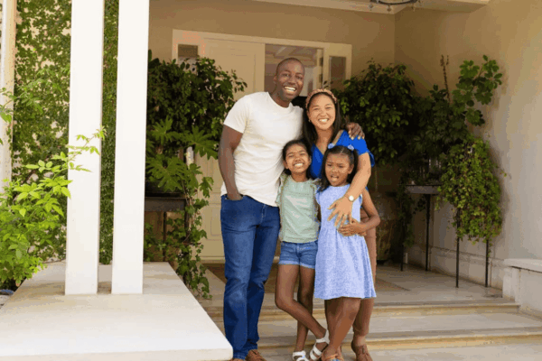 Happy family standing outside their home, representing homeowners exploring HELOC options for debt consolidation.