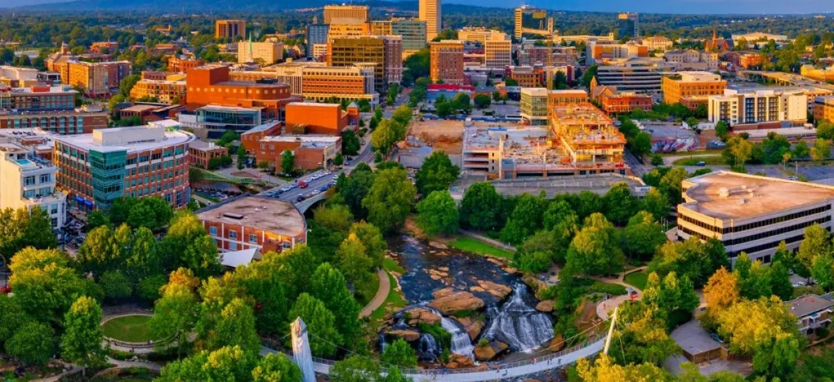 Aerial view of Greenville SC skyline and Falls Park waterfall, highlighting the city’s booming real estate and housing market in 2025.